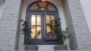 A building entrance with a blue arched window, two potted plants, and a colorful hanging light fixture. - Magnolia Guest House (Varkala)