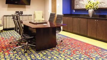A conference room with a large table, chairs, a television, and a decorative wall piece.