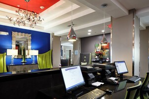 Zona de recepción de un hotel, con mostrador, computadoras y teléfono.