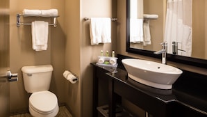 A modern bathroom with a toilet, sink, and mirror. There are towels on a rack and a shower curtain. - Holiday Inn Express Hotel & Suites El Reno by IHG (El Reno)