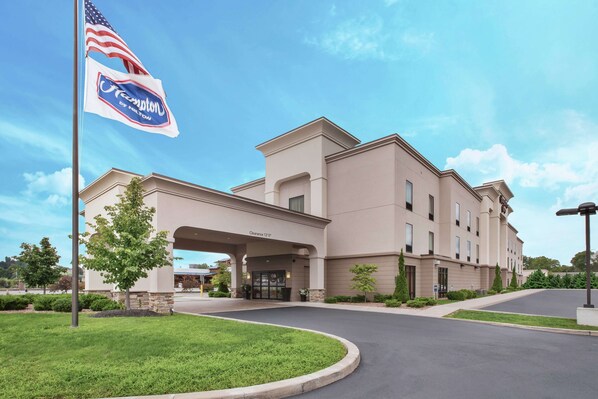 A hotel with a beige exterior, a clear sky, and a well-maintained lawn.