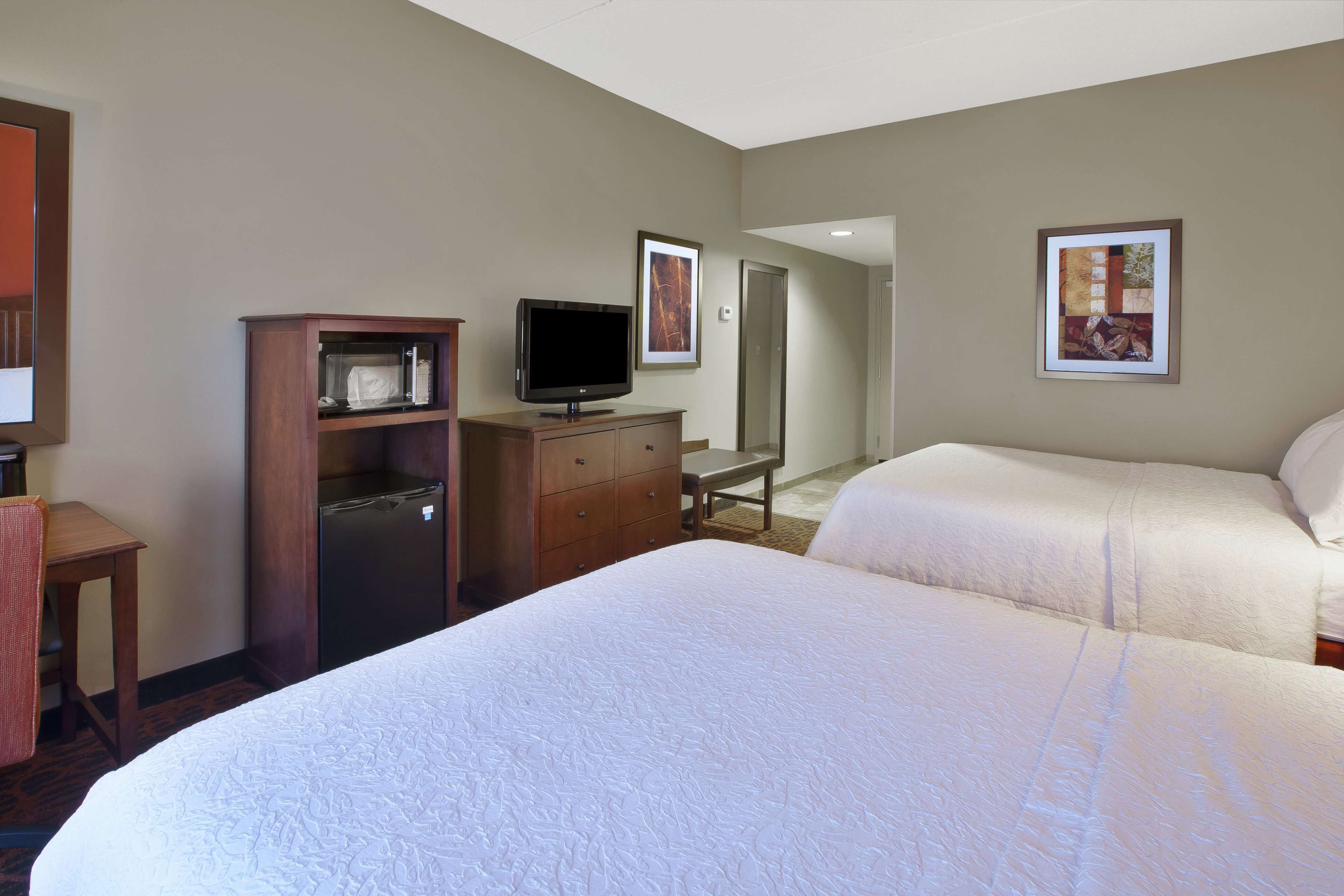 A hotel room with two beds, a TV, a desk, and a microwave.