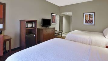A hotel room with two beds, a TV, a desk, and a microwave.