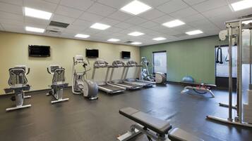 Un gimnasio con cintas de correr, elípticas y equipo de levantamiento de pesas.