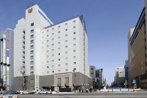 Un hotel de varios pisos con un diseño moderno, que destaca por una entrada imponente y numerosas ventanas.