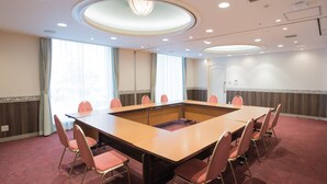 A conference room with a large table, eight chairs, and a carpeted floor.
