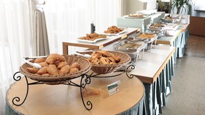 A buffet setup with various food items and baskets of pastries.