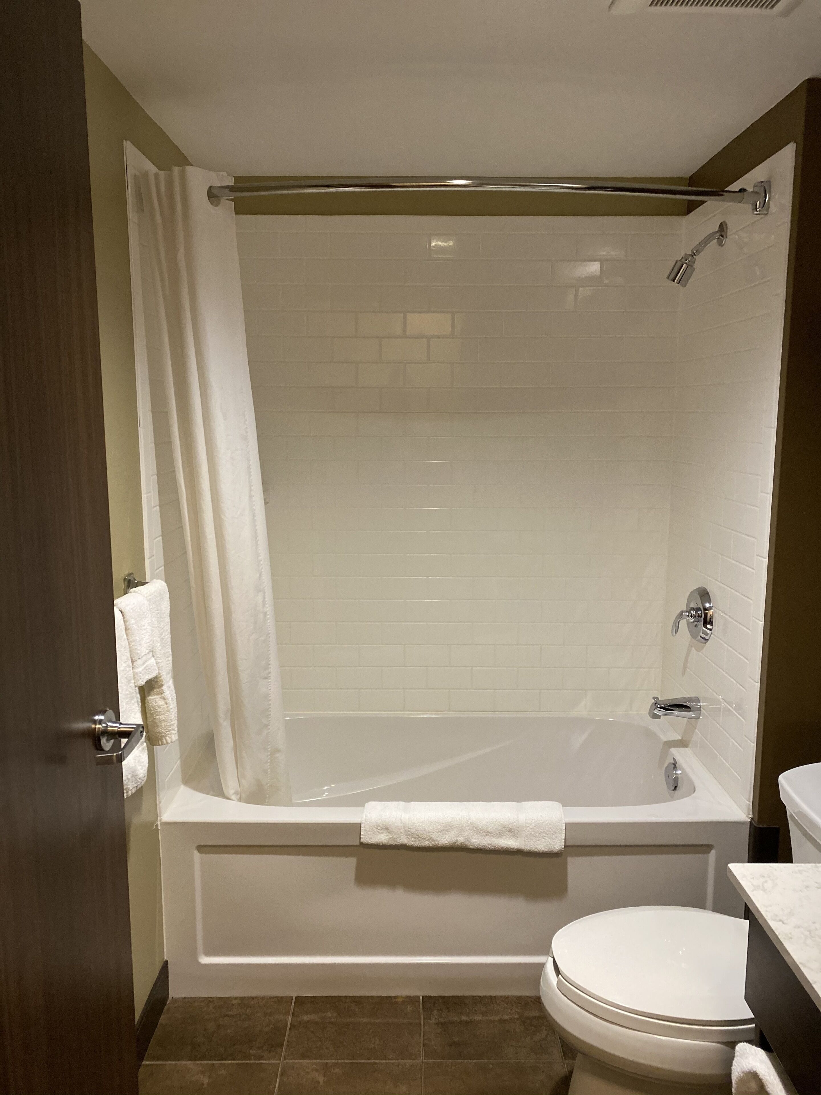 A bathroom with a bathtub, toilet, and shower curtain.