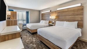 Une chambre d’hôtel avec deux lits, un bureau, une lampe et une fenêtre avec des rideaux.
