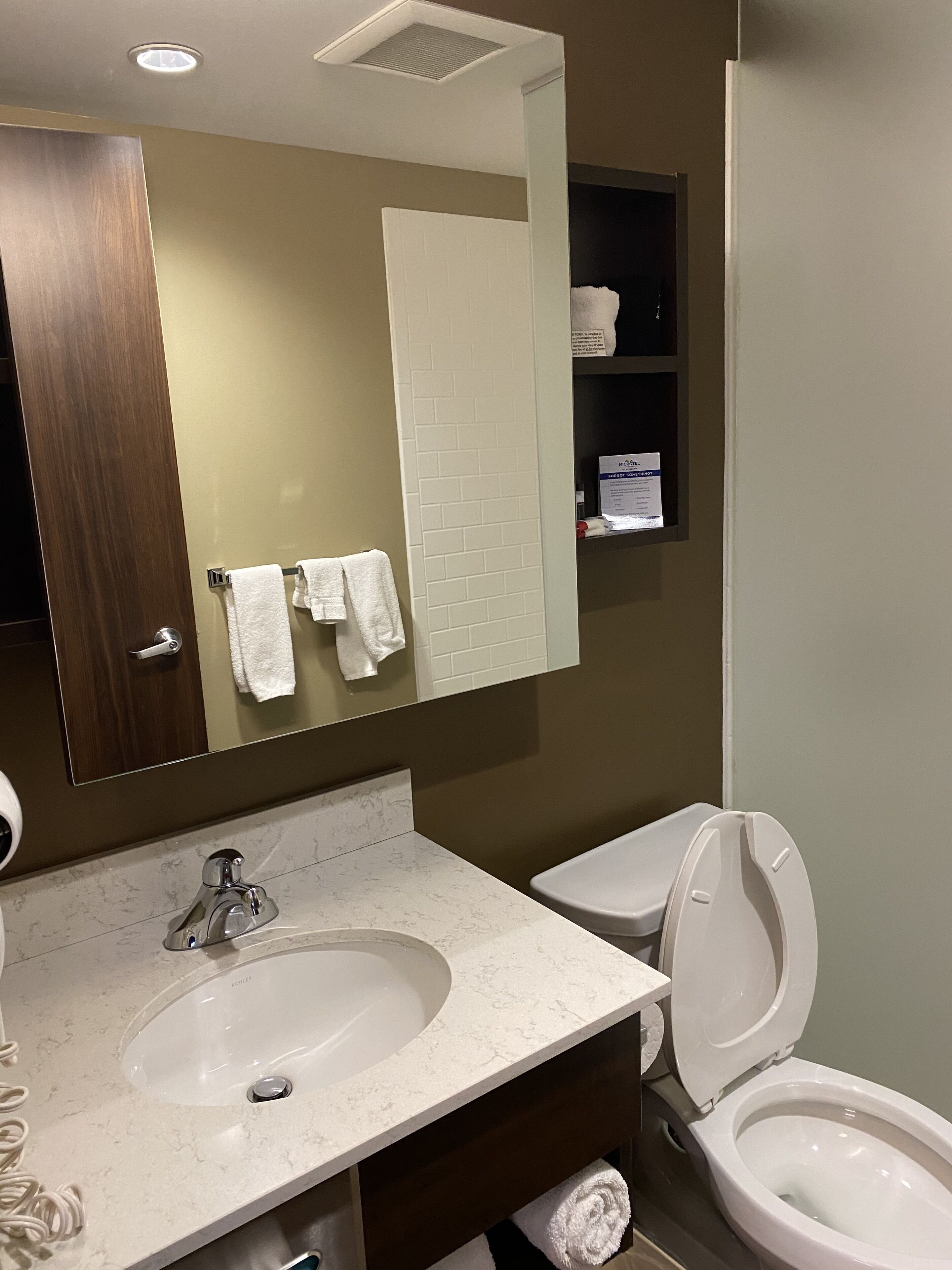 A bathroom with a sink, mirror, toilet, and towel rack.