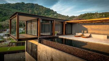 A modern outdoor pool area with a glass-enclosed lounge and a view of a forested hillside.