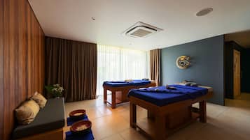 A room with a bed, two massage tables, a small sofa, and a window with curtains.