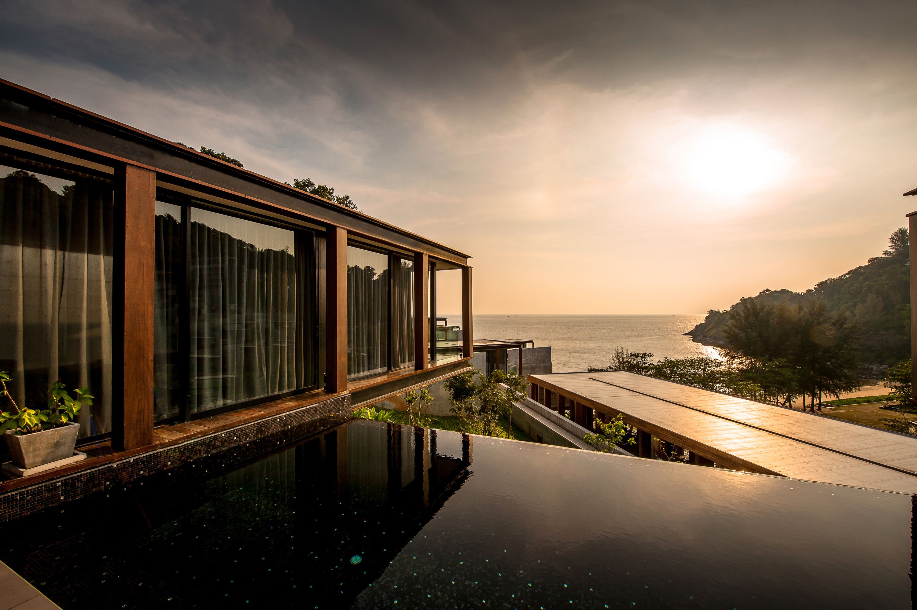 A modern building with a glass facade overlooking a body of water.