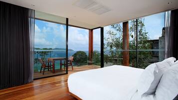 Une chambre moderne avec un grand lit, un plancher en bois, un balcon avec une table et des chaises, et une vue sur la mer.