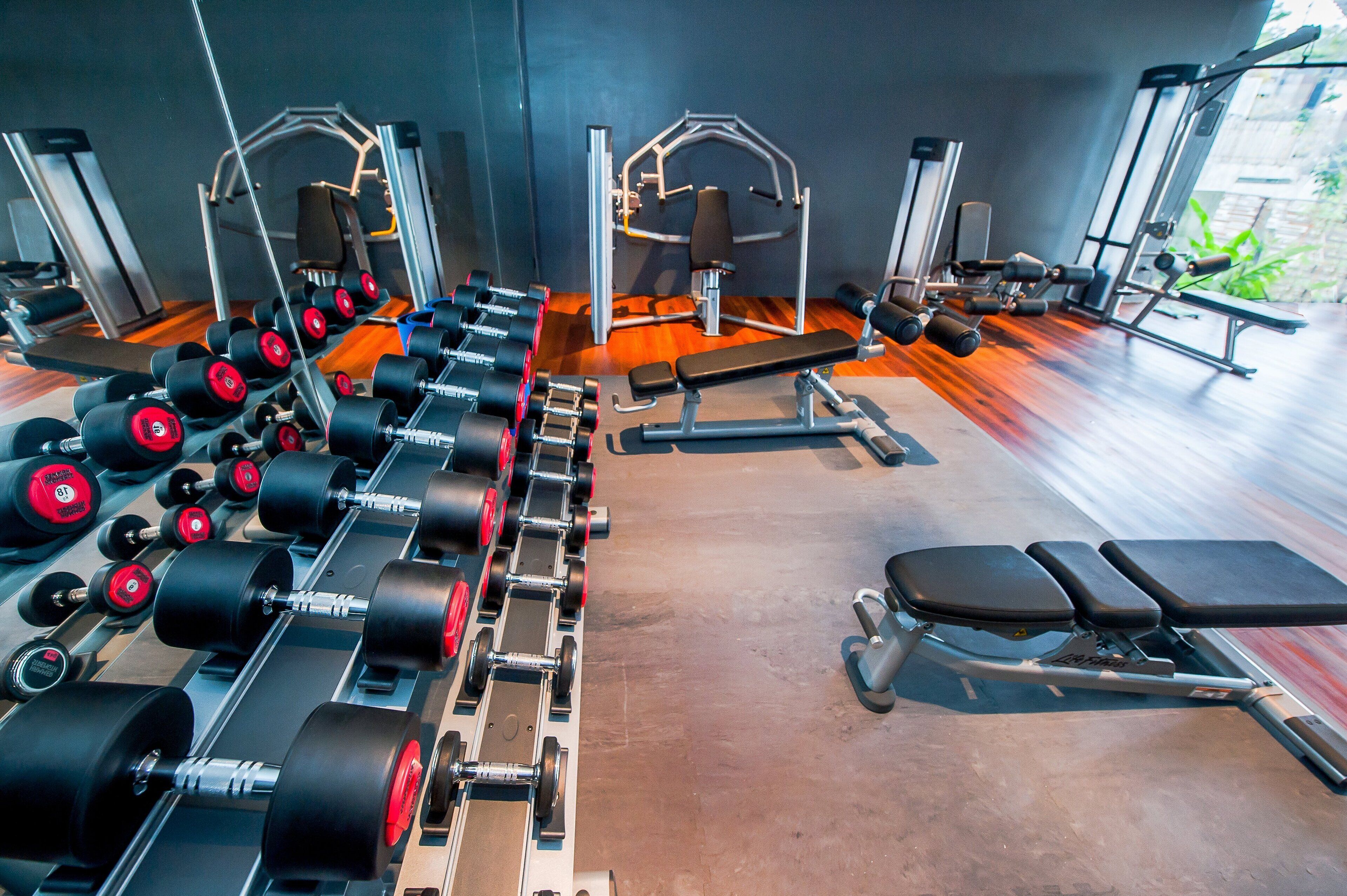A gym with various exercise equipment, including dumbbells, benches, and weight machines.