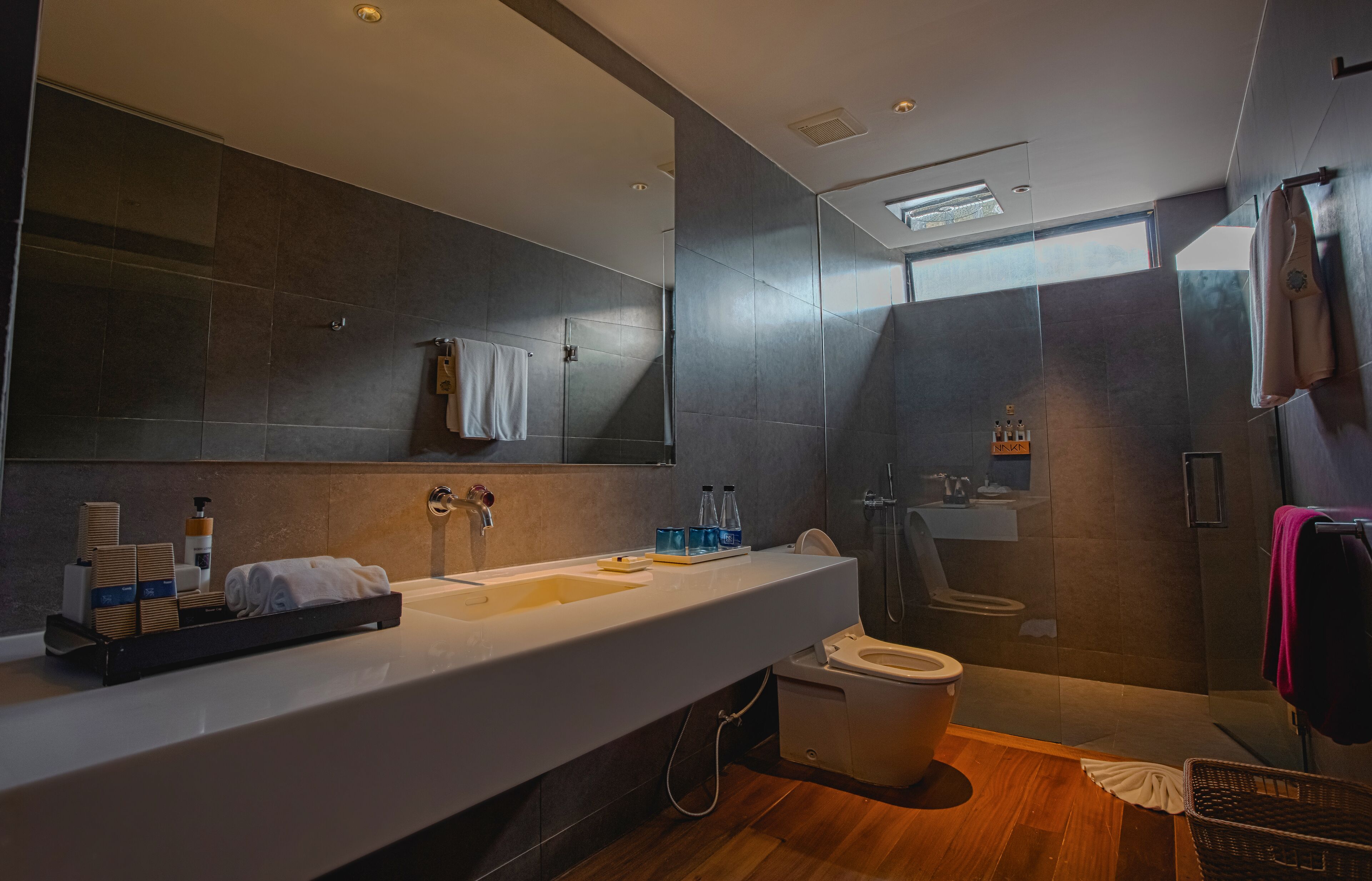 A modern bathroom with a large mirror, a sink, a toilet, and a shower area.