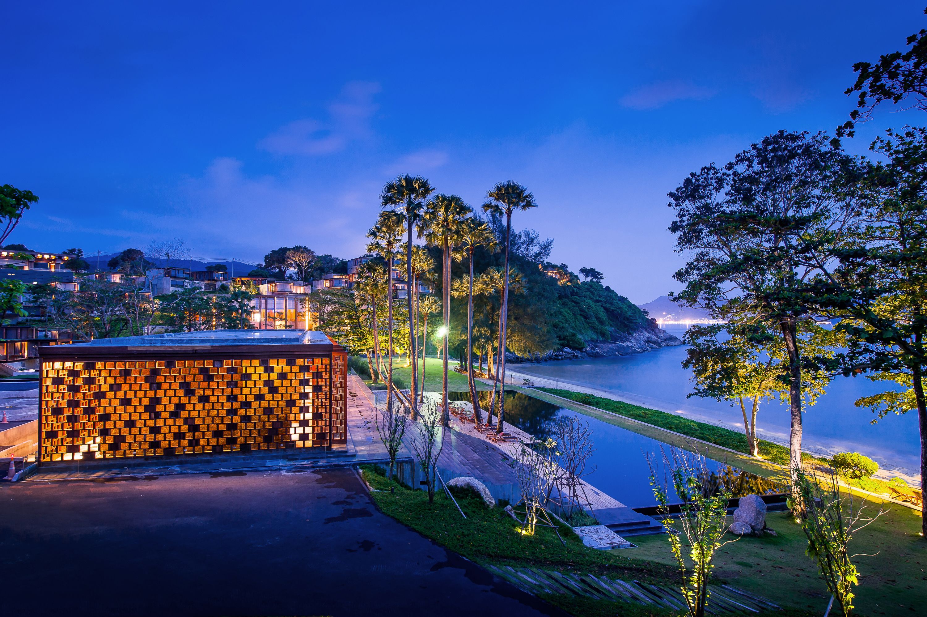 A riverside view with a wooden structure, a bridge, and a distant mountain range.