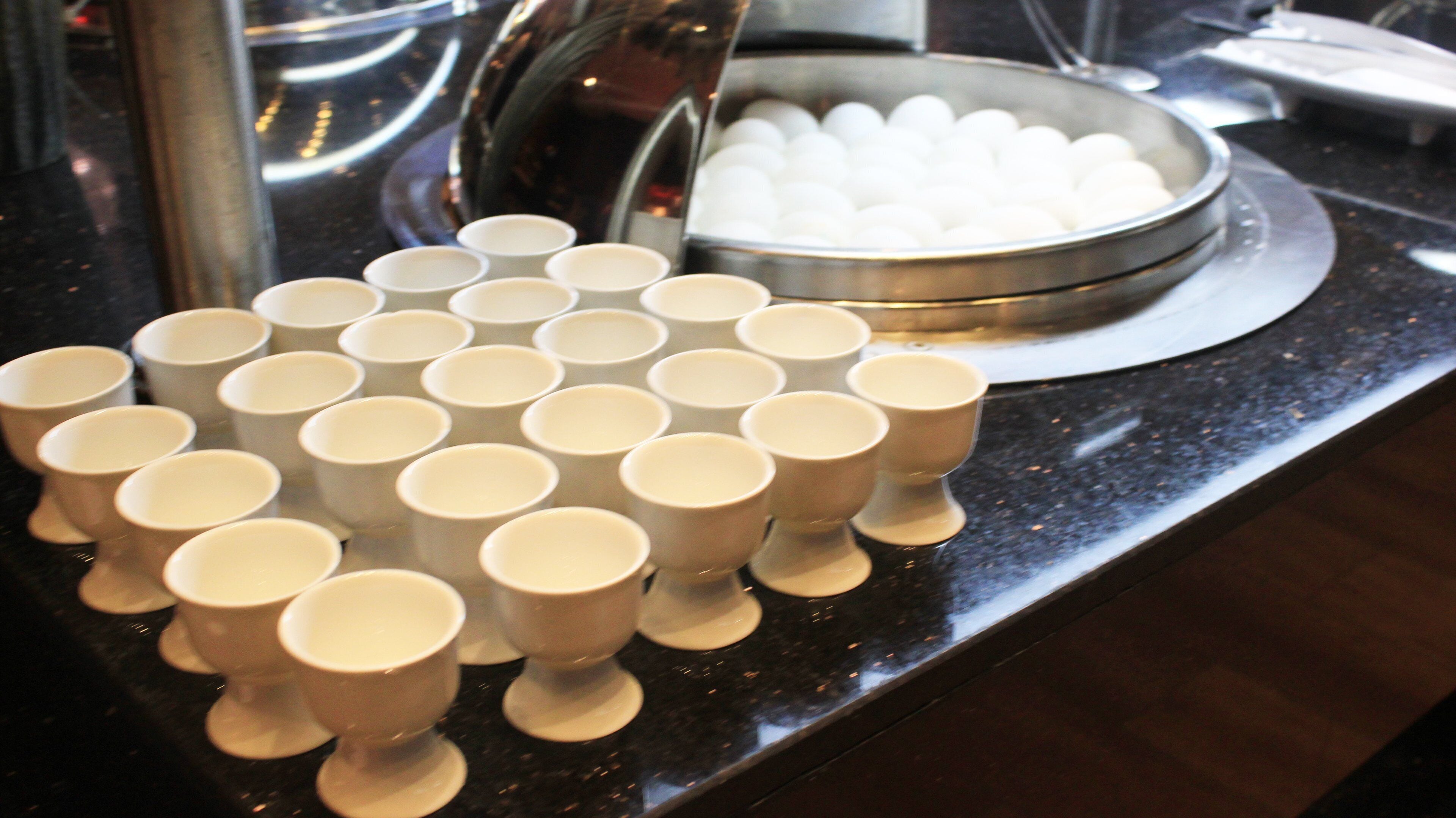 Una mesa con varios cuencos y tazas blancos dispuestos en un mostrador tipo bufé.