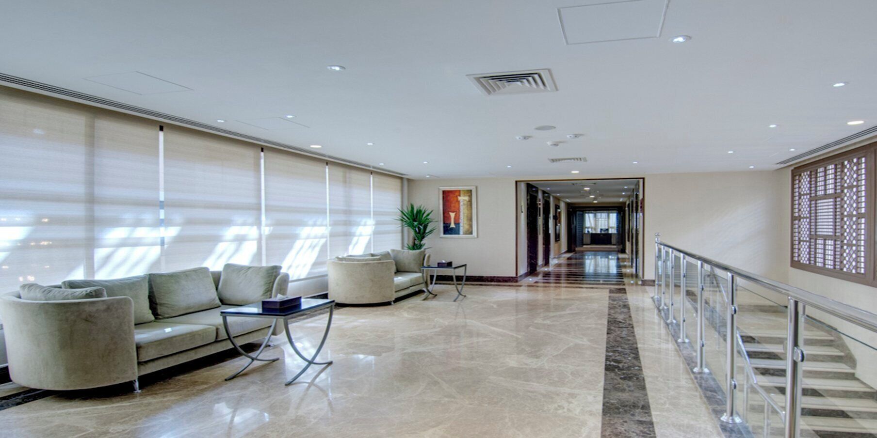 A spacious lobby with a seating area, a plant, and a view corridor.