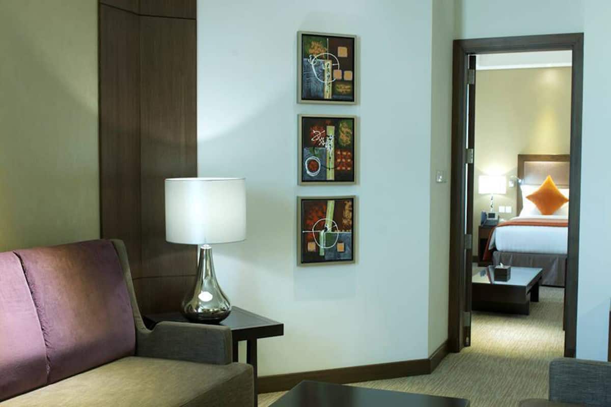 Ein Hotelzimmer mit einer Couch, einer Lampe und drei gerahmten Kunstwerken an der Wand.