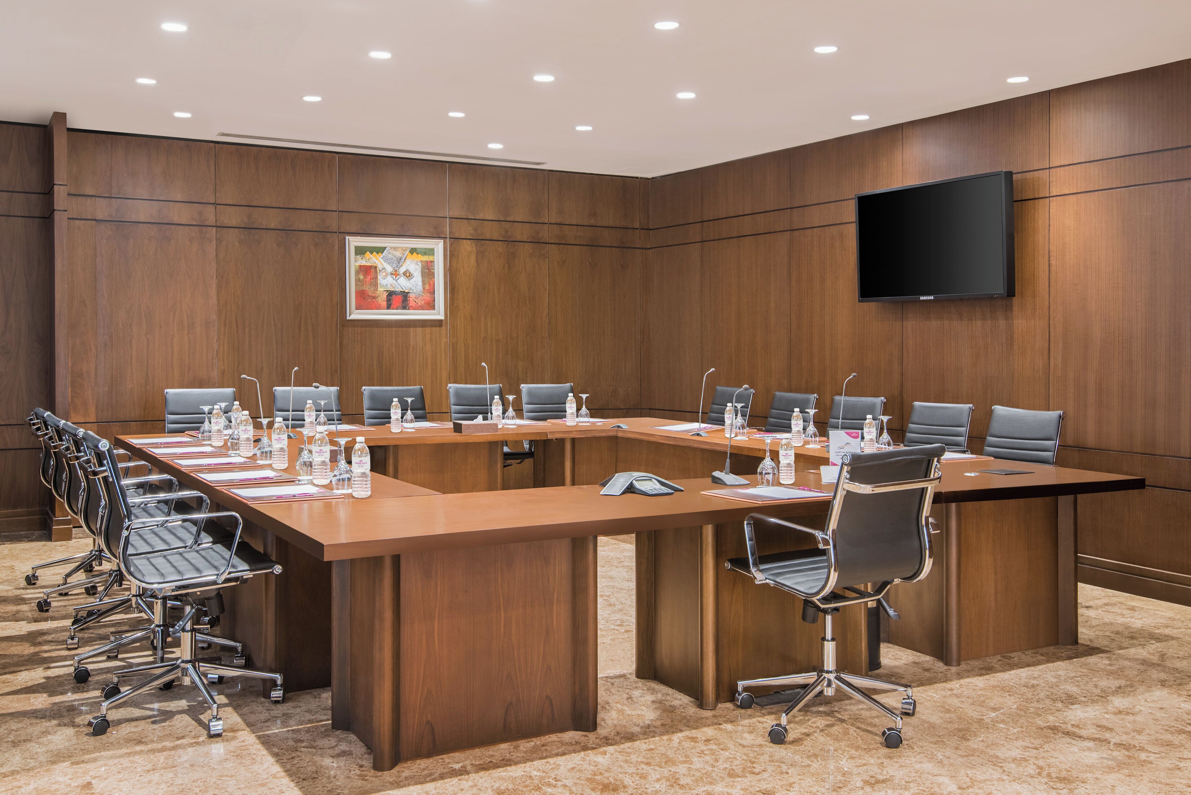 A conference room with a long table, chairs, and a flat-screen TV on the wall.