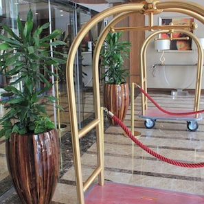 A lobby area with a gold-framed entrance, potted plants, and a red rope barrier. - Crowne Plaza Madinah by IHG (Madinah)