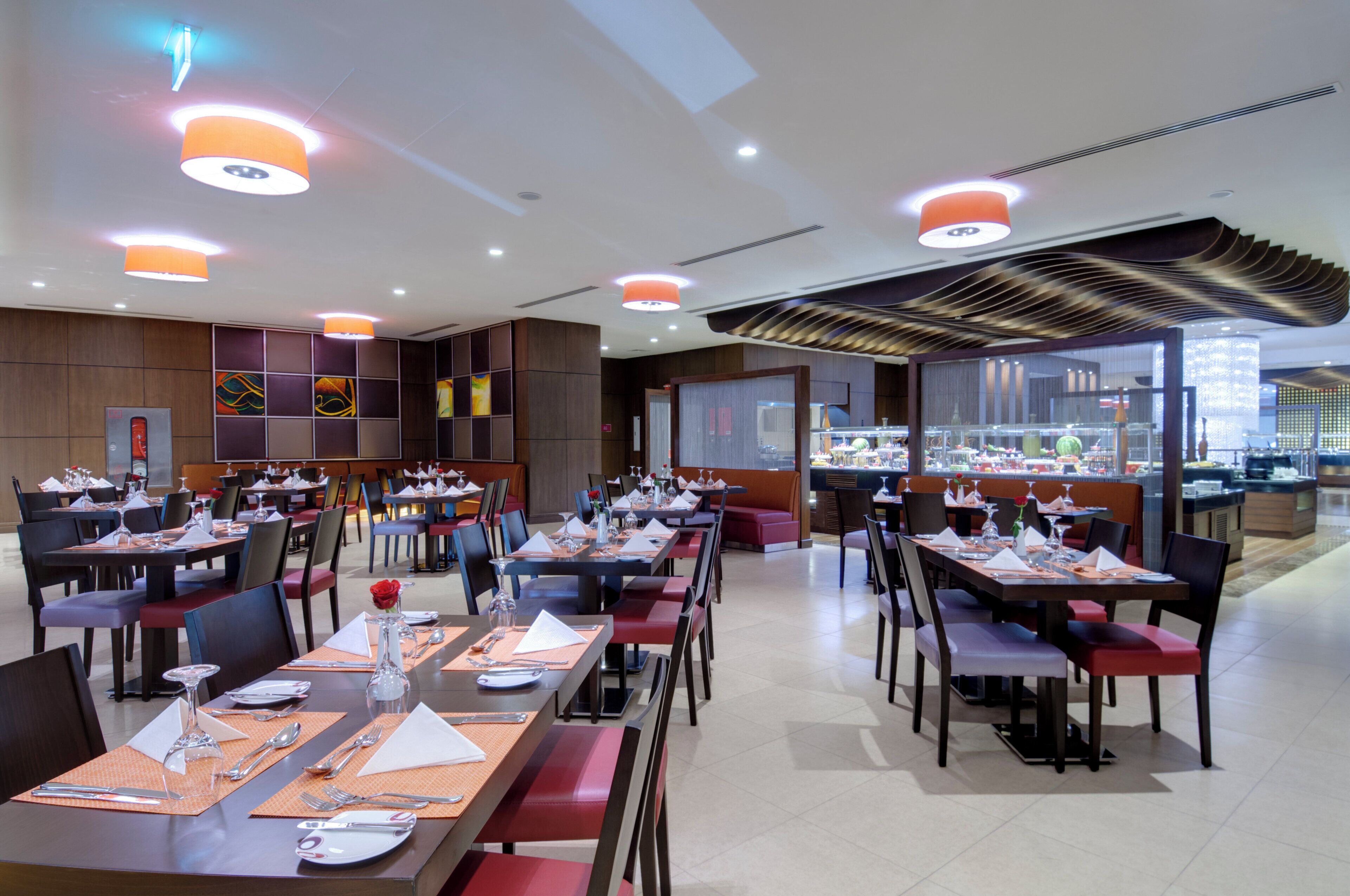 A restaurant with multiple dining tables, chairs, and a variety of table settings.