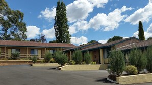 A motel with multiple rooms, a parking lot, and surrounding greenery.