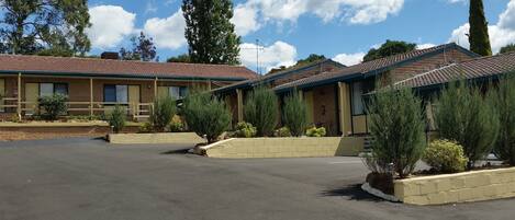 A motel with multiple rooms, a parking lot, and surrounding greenery.