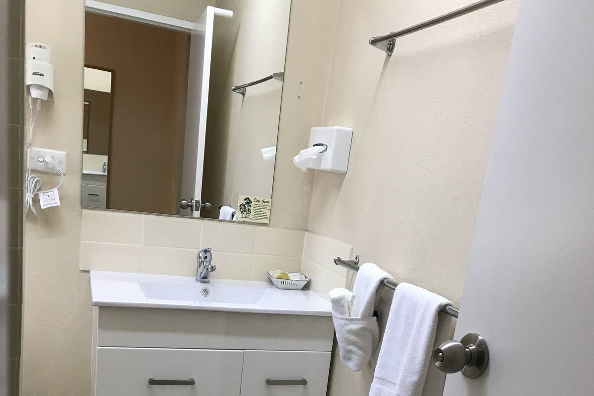 A bathroom with a sink, mirror, towel rack, and tiled floor.
