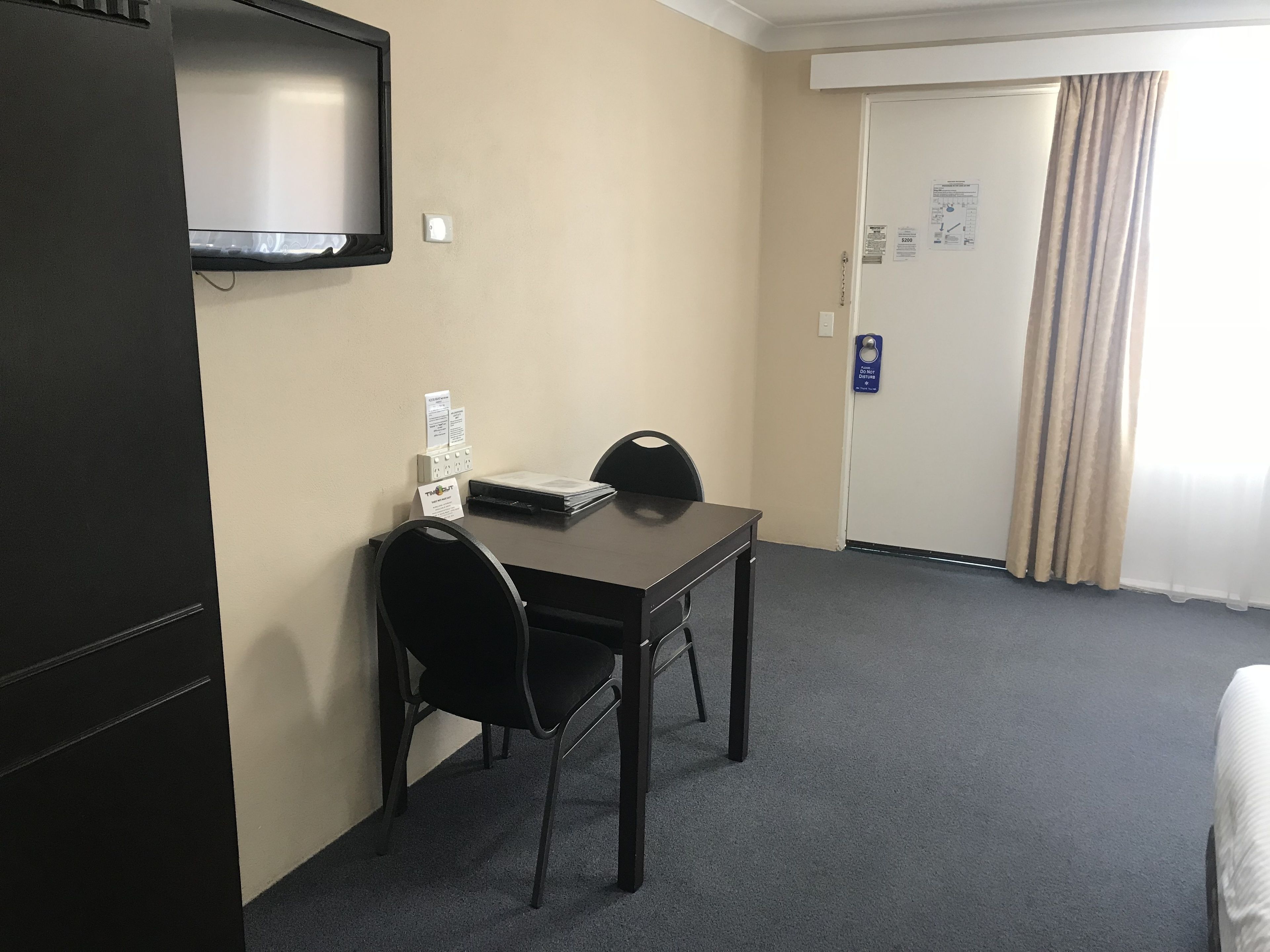 Una habitación de hotel con escritorio, silla y televisor montado en la pared.