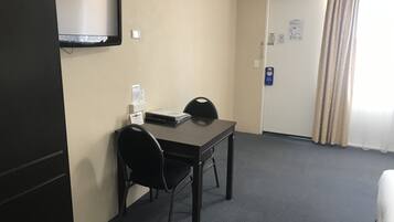 Una habitación de hotel con escritorio, silla y televisor montado en la pared.