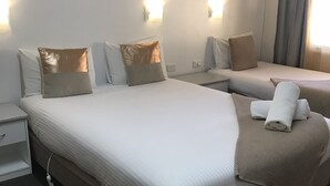 A hotel room with a large bed, two bedside tables, and a window with curtains.