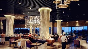 Un restaurante espacioso con techos altos, pilares grandes y modernas luminarias.