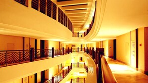 Interior de un hotel con varios niveles, un atrio central, balcones y un diseño de techo curvo.