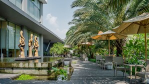 Un espacio exterior moderno con fuente de agua, mobiliario y sombrillas.