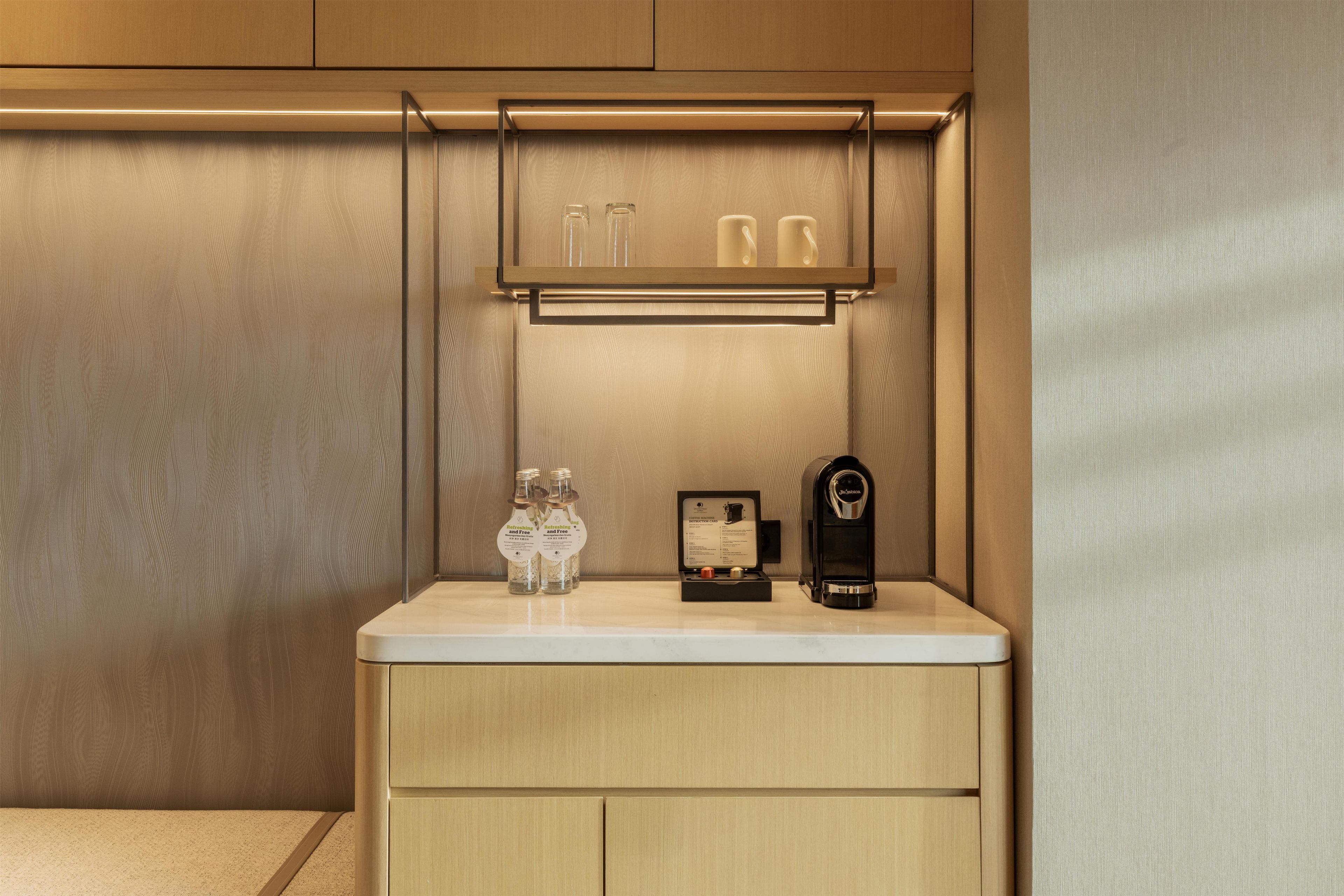 A bathroom with a wooden vanity, a coffee machine, and a bottle of hand soap.