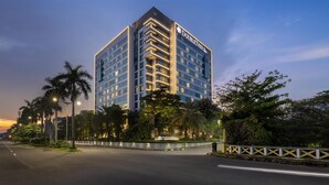 Un hotel moderno con un llamativo letrero de "DoubleTree", rodeado de exuberante follaje y palmeras.