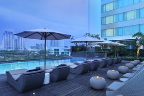 A rooftop pool area with lounge chairs and umbrellas, overlooking a cityscape. - DoubleTree by Hilton Jakarta Kemayoran (Jakarta)