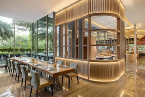 A modern dining area with a long table, chairs, and a view of greenery outside. - DoubleTree by Hilton Jakarta Kemayoran (Jakarta)