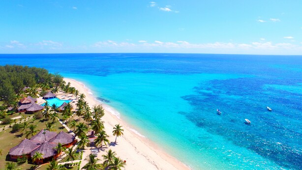 A beach resort with thatched-roof huts, a swimming pool, and palm trees. - Nosy Saba Private Island & Spa (Nosy Saba)
