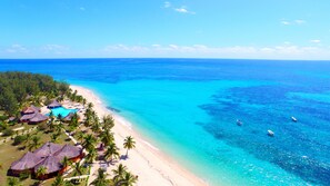 A beach resort with thatched-roof huts, a swimming pool, and palm trees. - Nosy Saba Private Island & Spa (Nosy Saba)