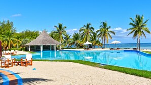 A poolside area with lounge chairs, a thatched-roof pavilion, and palm trees. - Nosy Saba Private Island & Spa (Nosy Saba)