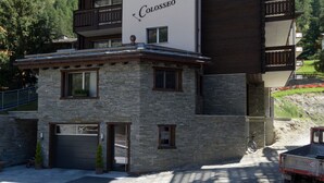 A hotel with a stone facade, balconies, and a sign reading "Colosseo". - Haus Colosseo by Zermatt Premium Apartments (Zermatt)