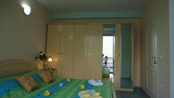 A bedroom with a bed, a nightstand, a wardrobe, and a view of the outside.