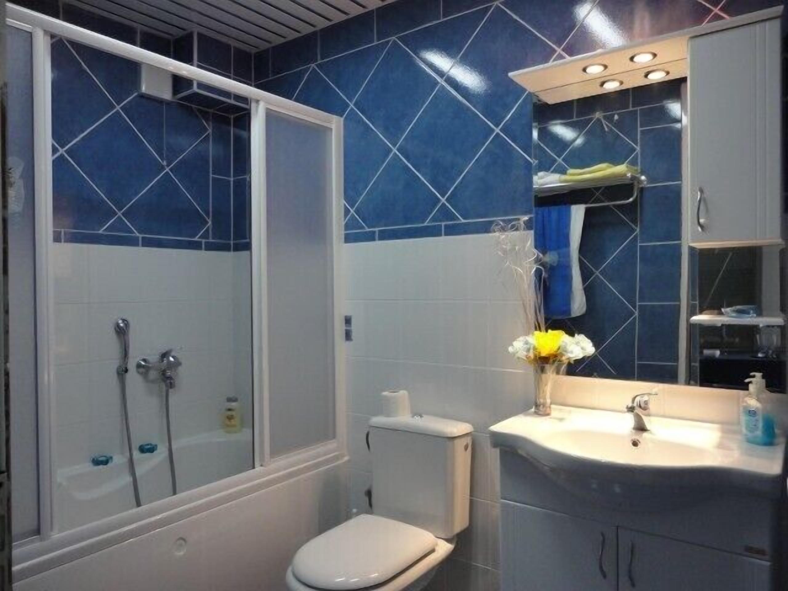 A bathroom with a shower, toilet, sink, and a mirror with a towel hanging.