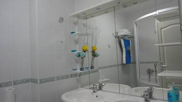 Um banheiro com duas pias, um espelho e um chuveiro.