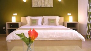 A bedroom with a bed, two bedside tables, a nightstand, a vase with flowers, and a painting on the wall. - Accommodation J&T (Ohrid)