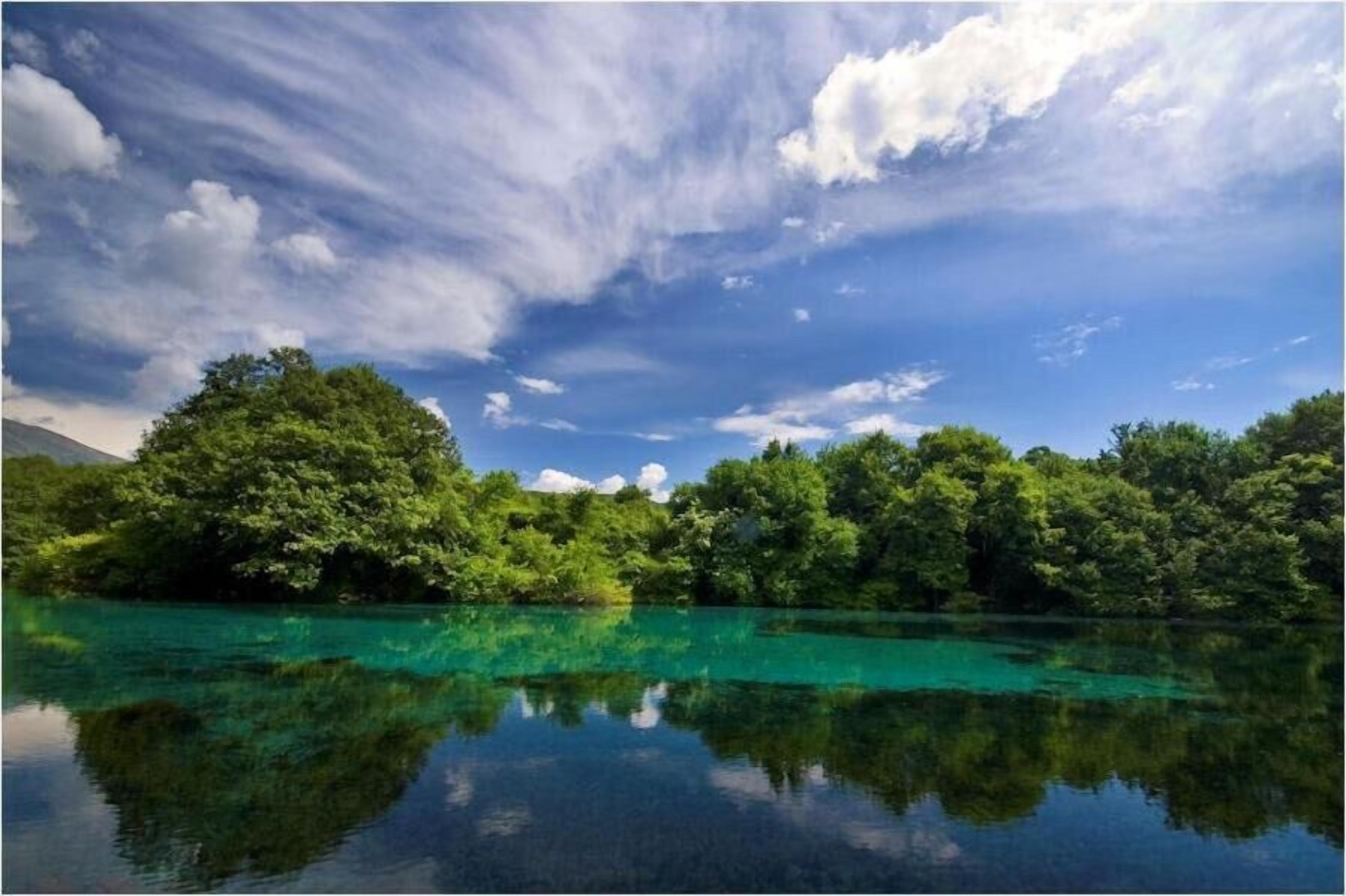 A serene lake with clear water reflecting the surrounding greenery and a partly cloudy sky.