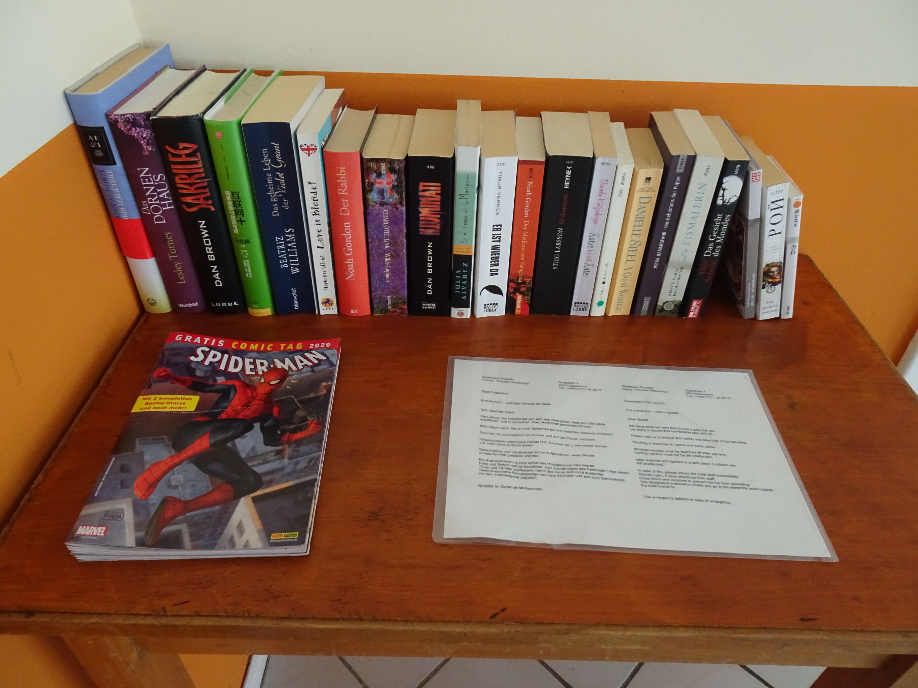 Ein Holztisch mit einer Stapel Bücher und einem Spider-Man Comic.